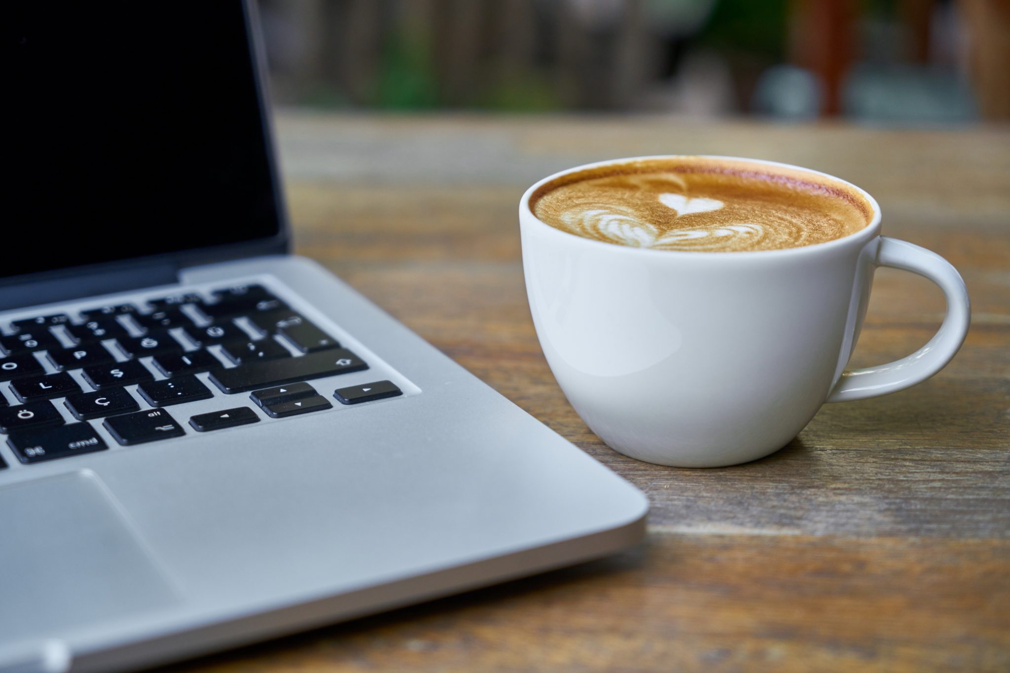 ein laptop steht auf einen Tisch neben einer Tasse Kaffe