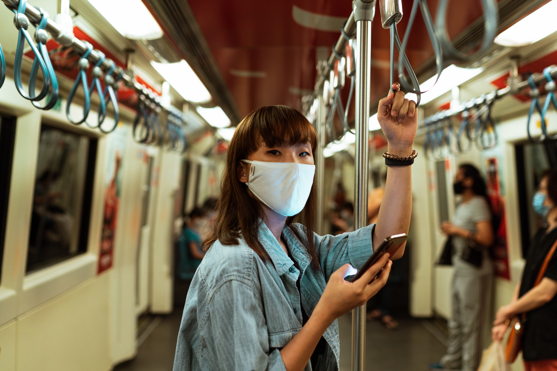 Frau steht in U-Bahn mit dem Handy in der Hand