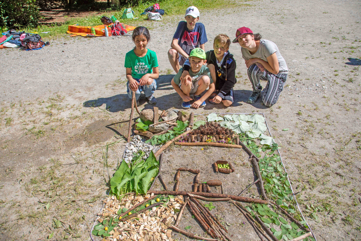 Therapeut:Innen machen mit Kindern mit gesammelten Materialien aus dem Wald ein Naturbild